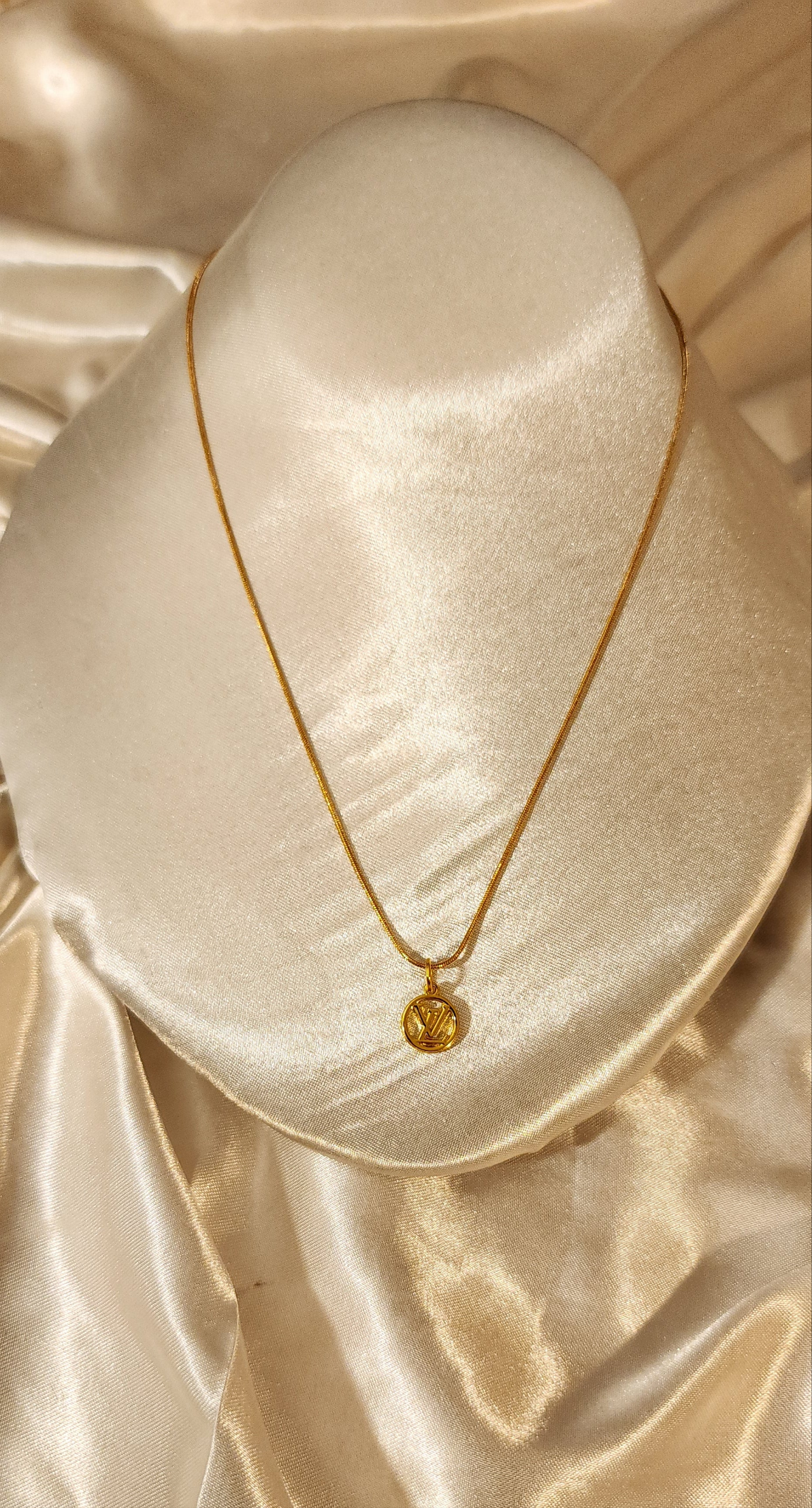 Repurposed vintage charm necklace from LV Era Collection with a round monogram pendant and a solid sterling silver chain plated in gold vermeil.