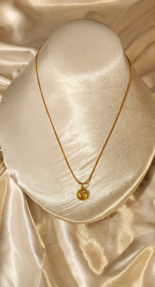 Repurposed vintage charm necklace from LV Era Collection with a round monogram pendant and a solid sterling silver chain plated in gold vermeil.